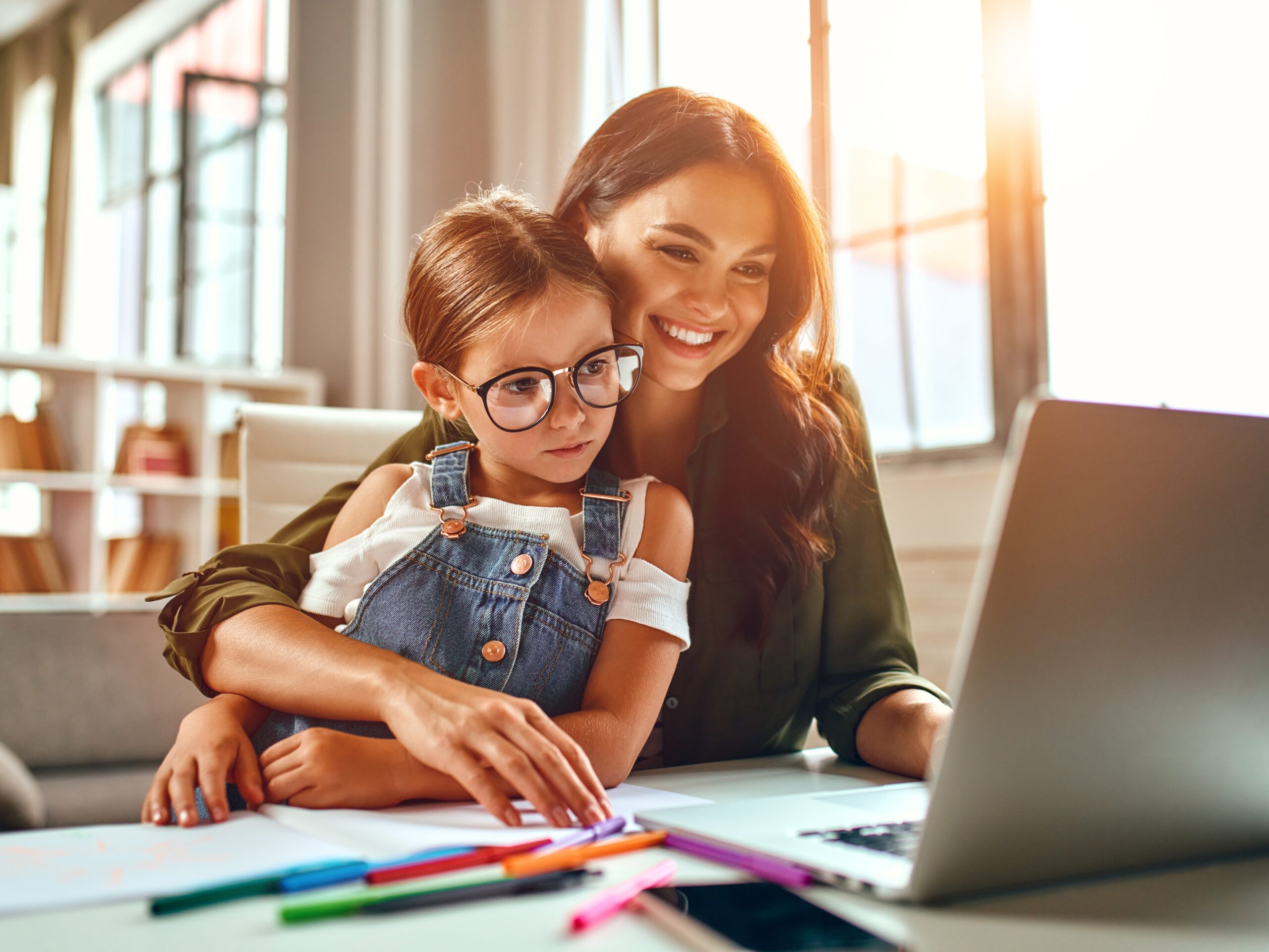 Woman scheduling her child's activities at a laptop on a summer day.